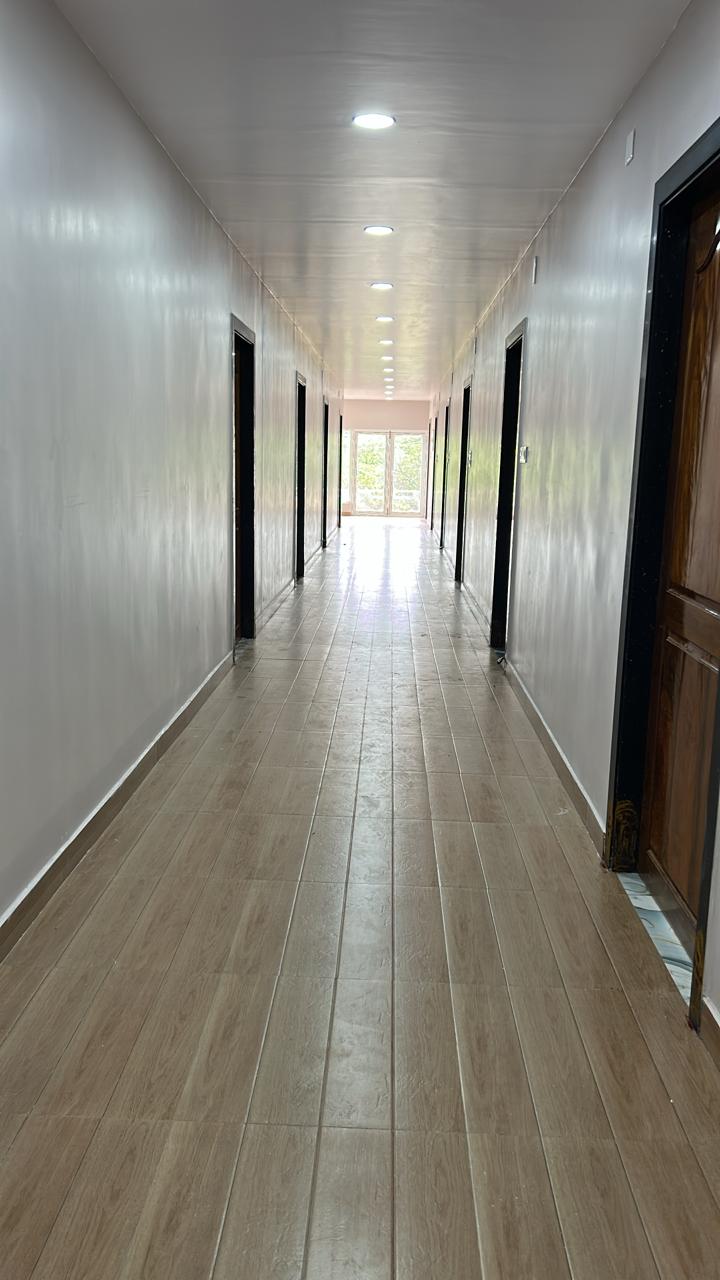 Guest room corridor with bright ceiling lights and room doors at Surabhi SJN Convention Hall