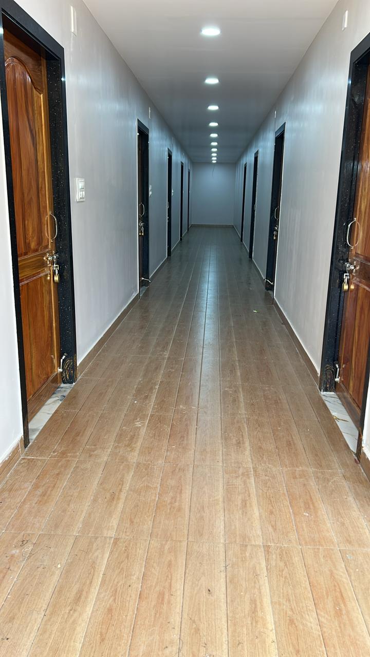 Guest room corridor with wooden doors and bright ceiling lights at Surabhi SJN