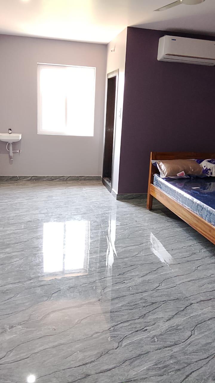 Purple accent AC room with bed and glossy floor at Surabhi SJN