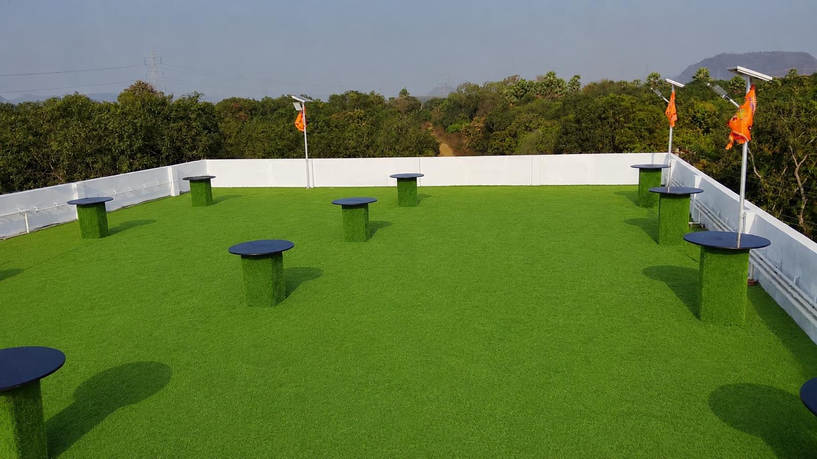 Open rooftop lawn with green turf at Surabhi SJN